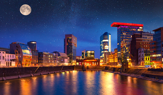 Colorful night scene of Rhein river at night in Dusseldorf. Medienhafen in the soft night light with stars and full moon, Nordrhein-Westfalen, Germany, Europe.