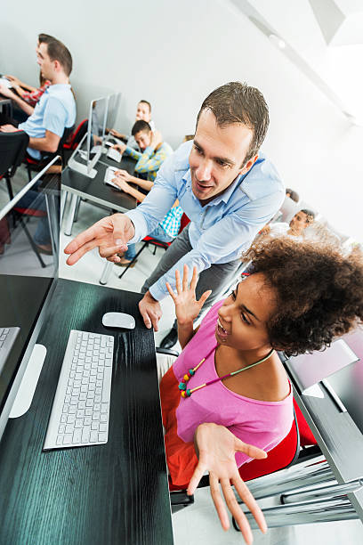 istock Teacher assisting African American female student at computer class. 473709620