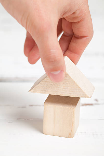 istock Wooden toy house with hand on white table 473709664