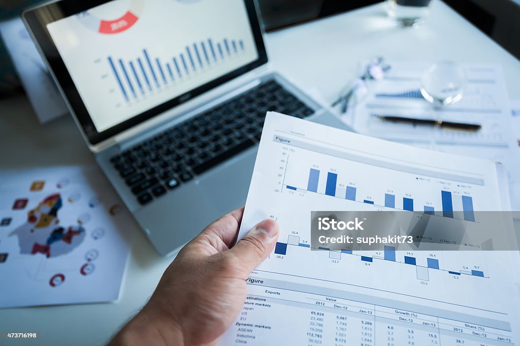 Report profits. Businessman checking reported profits on the paper and laptop. 2015 Stock Photo