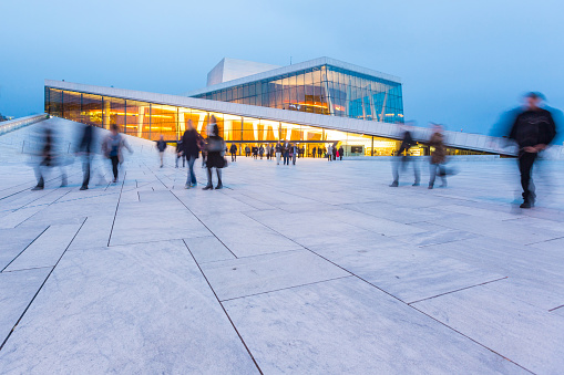 Oslo, Norway - April 18, 2015: Blurred people in front of Opera House at twilight. This is the home of the Norwegian National Opera and Ballet. Norwegian name is Operahuset. Long exposure shot.