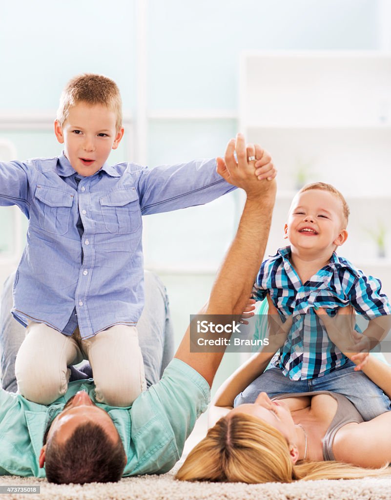 Happy parents playing with their small children and having fun. Playful family having fun on carpet at home. 2015 Stock Photo