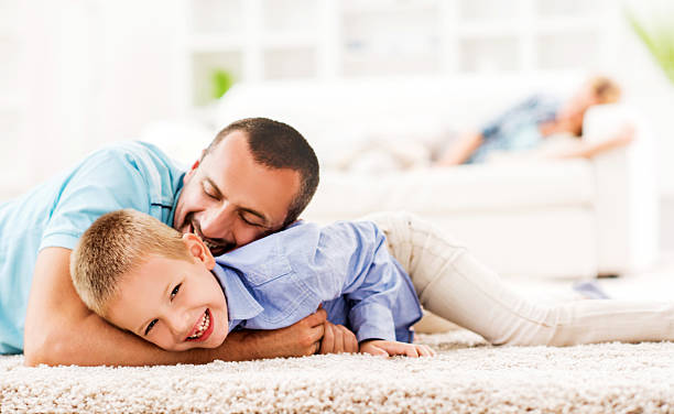 istock Cheerful father and son having fun on carpet at home. 473737806