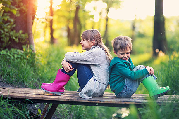 istock Brother and sister sitting on bridge in forest 473738914