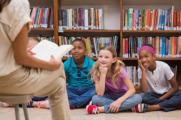 istock Three young students listening to a story in the library 473742276