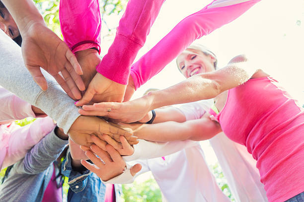 istock Team with hands in huddle at breast cancer awareness race 473745190