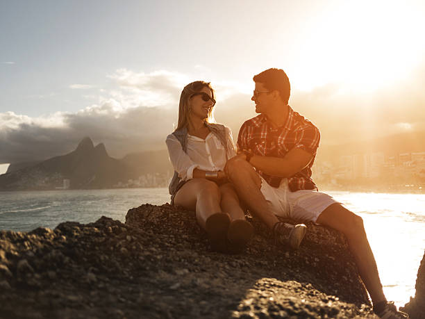 istock Smiling Latin American couple talking on a rock at sunset. 473745906