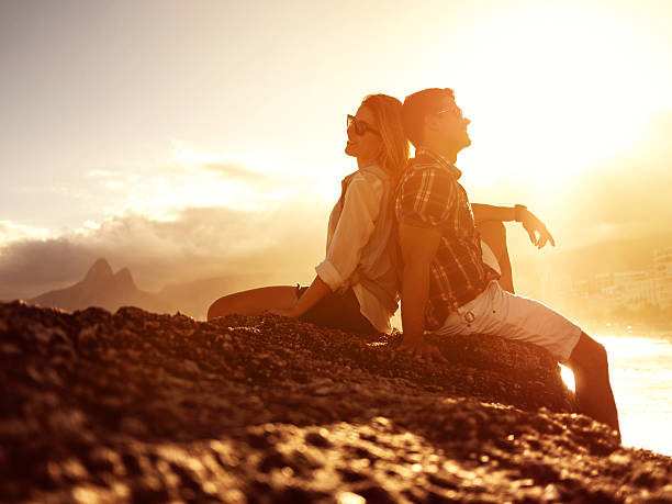istock Smiling Hispanic couple sitting back to back on a rock. 473745926
