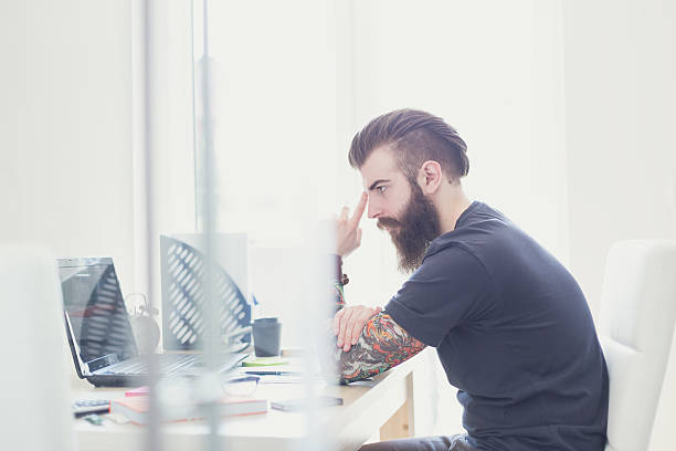 istock Hipster with tattooed arms in office 473762458