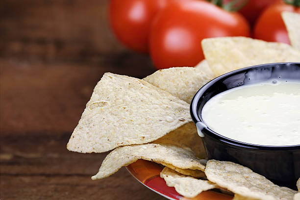 Bowl of Queso Blanco White Cheese Sauce Queso Blanco or White Cheese Sauce with corn tortilla chips and fresh tomatoes. Extreme shallow depth of field with selective focus on cheese dip. cheese dip stock pictures, royalty-free photos & images