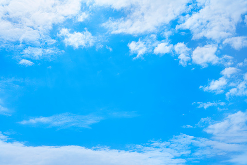 A DSLR photo of white clouds in a blue summer sky. Can be used as a background. Much space for copy.