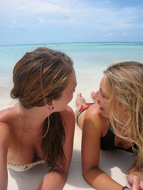 Two Girls Lounging on the White Sand Beach in Cancun stock photo