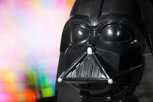 Paris, France - May 14, 2015: image of plastic figurine part Lewis Galoob toys (1994), Micro Machines, head portrait mask costume of Darth Vader character, represents the Dark Side of the force, and he is the Luke Skywalker's father. Head portrait of Darth Vader which has been shot on colored light painting background. He is a fictional main character personnage, from the Star Wars saga films created by George Lucas in 1977 (LucasFilm ldt).