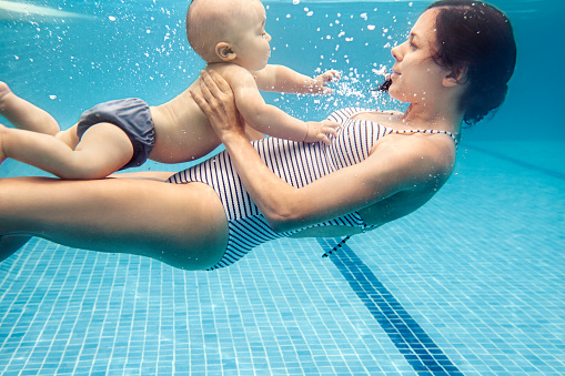 Mother swimming with baby boy