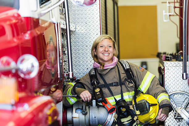 bombero mujeres de pie al lado de camión de bomberos en la estación - fire department heroes portrait occupation fotografías e imágenes de stock