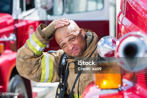 istock Serious African American firefighter next to fire trucks 473790408