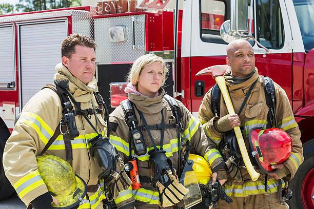 istock Firefighters in protective gear with fire rescue trucks 473790410