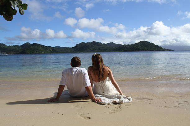 Bride & Groom Sitting on Sand in Fiji stock photo