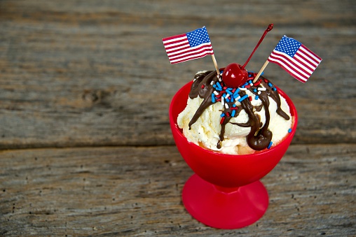 Pair of American flags on a chocolate sundae with red, white and blue sprinkles.