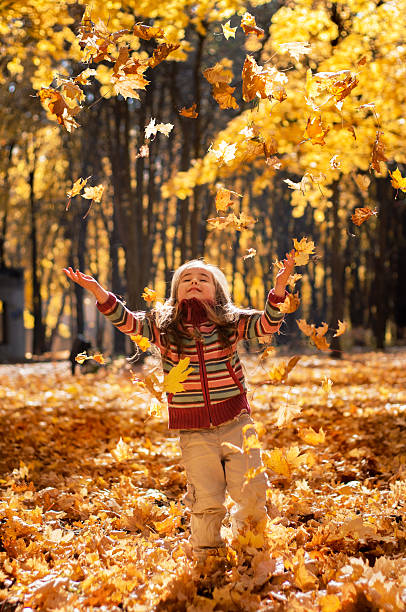 istock Little happy girl throws up fallen leaves 473800878