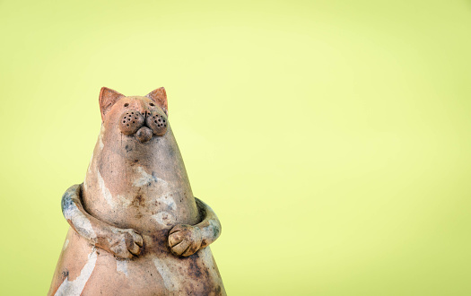 Chubby cat clay figure with large copy space for your text / logo. Figure is self made. Vintage green background. Soft vignette. Soft post-processing. Photo made with high quality photo equipment in a modern photo studio. 