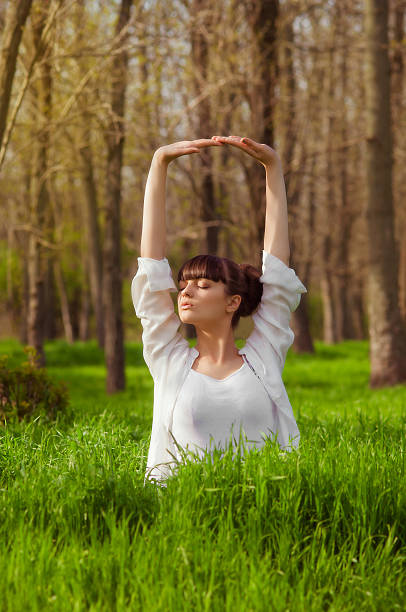 istock Young girl doing yoga on a green grass 473821330