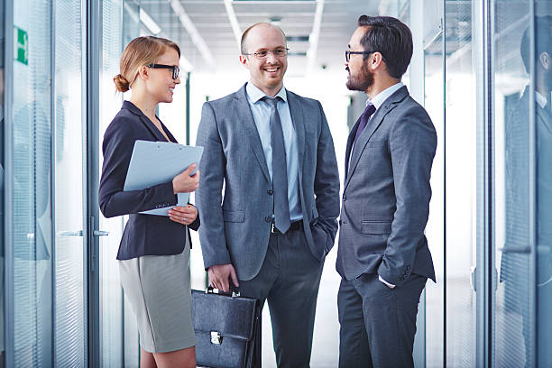 istock Three businesspersons on glass hallway during a discussion 473822608