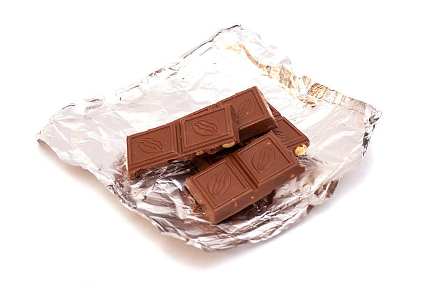 istock Broken Chocolate bar in foil isolated on white background 473822732