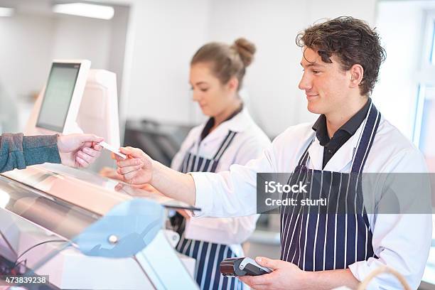 Taking Credit Card Payment In A Butchers Shop Stock Photo - Download Image Now - Butcher's Shop, Paying, 2015