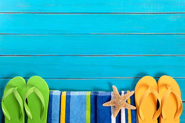 Summer beach themed background with flip flops and a towel