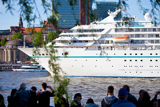 Hamburg, Germany - May 10, 2015: Hamburg harbor birthday celebration (Hafengeburtstag). One million visitors from around the world joined the world’s greatest port festival. Parade in front of the Landing Stages (Landungsbrücken), featuring more than 300 ships. Cruise ship MS Amadea with visitors in front.