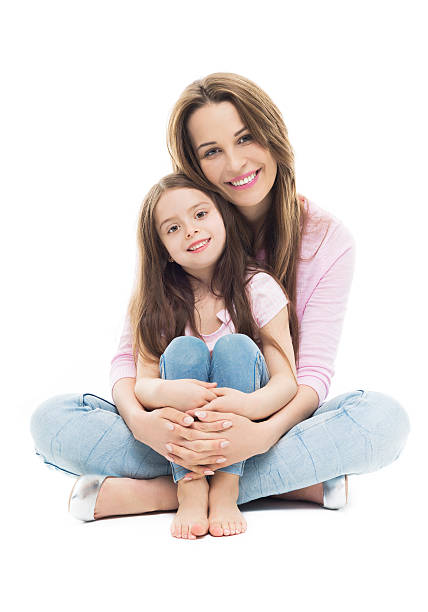 A latin teenage girl embracing her mother, closing her eyes and smiling in a horizontal waist up shot outdoors.
