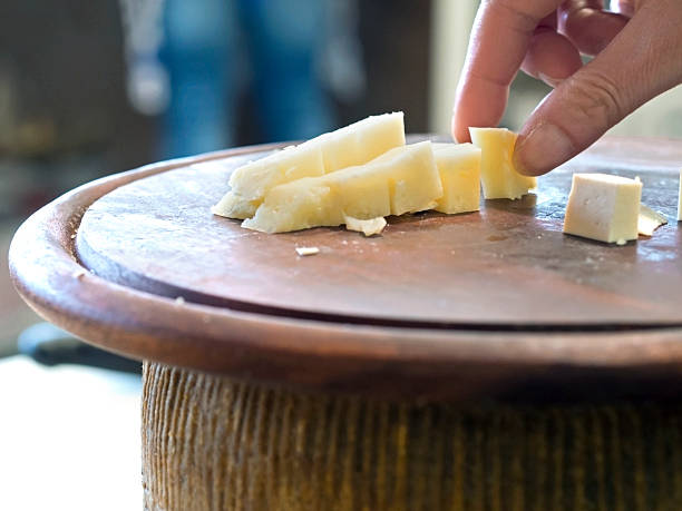 hand grasping cubes of cheese on wooden cutting board stock photo