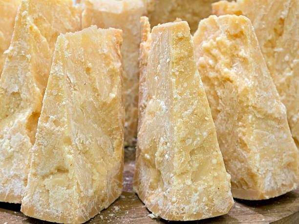 thick slices of Italian Parmesan cheese on  wooden cutting board stock photo