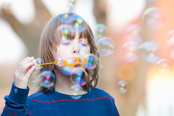 istock Boy with Blond Hair Blowing Bubbles 473856792