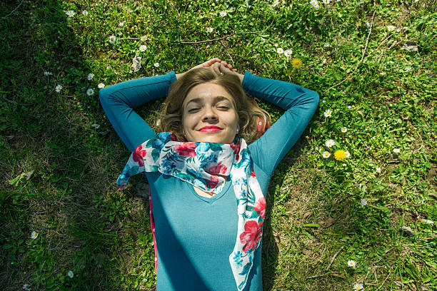 istock Young woman lying on the grass with hands above head 473868570