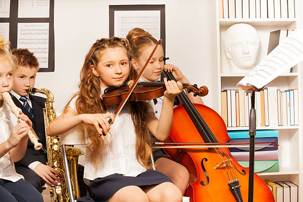 grupo de niños jugando instrumentos musicales en el interior - violin family fotografías e imágenes de stock