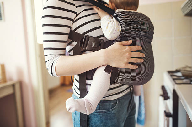 Mother with her daughter Young mother having her cute little daughter in baby carrier baby carrier stock pictures, royalty-free photos & images