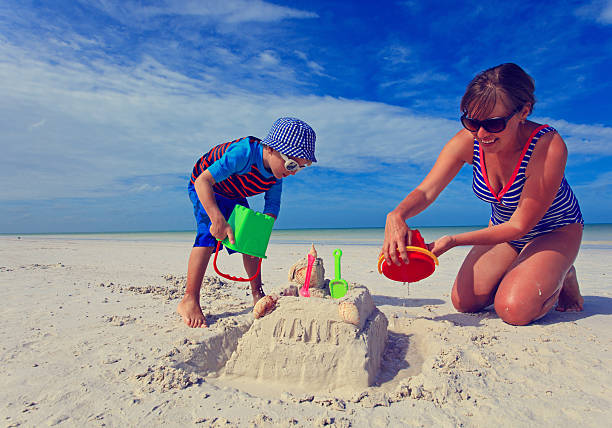 mutter und sohn bauen sandburgen am sommer strand - sandburg struktur stock-fotos und bilder