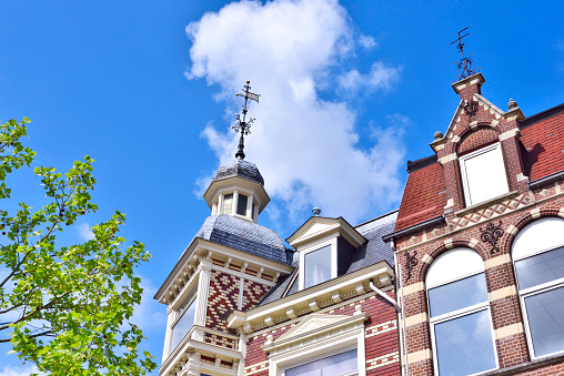 Historic house facade of the turn of the century, Netherlands. Old, ornamental lantern and old town on a sunny day with blue sky and fluffy clouds.