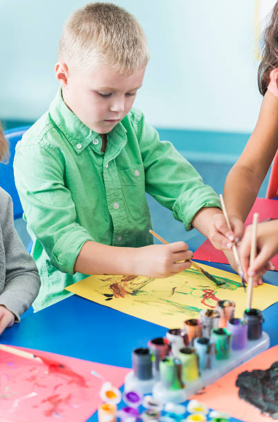 istock Little boy in art class painting a picture 473906130