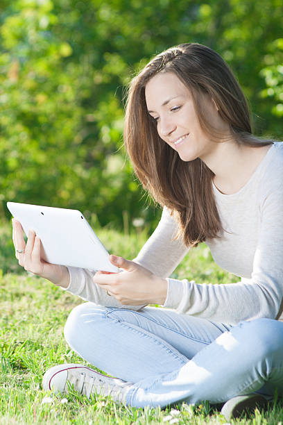 istock Young woman using digital tablet mobile outdoor. Smiling wearing jeans . 473906680