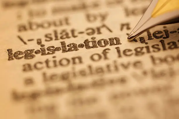 Legislation pen nib pointing to the words in the dictionary, shot with very shallow depth of field,