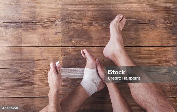 Injured Runner Wrapping His Left Ankle Stock Photo - Download Image Now - Physical Injury, Running, 2015