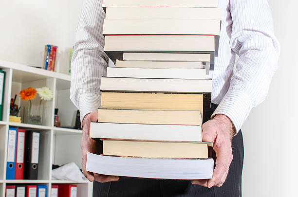 istock Man carrying a pile of books 473920120