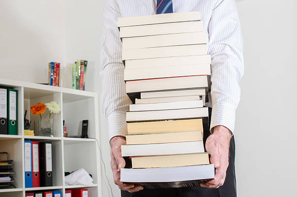 istock Man carrying a pile of books 473920126
