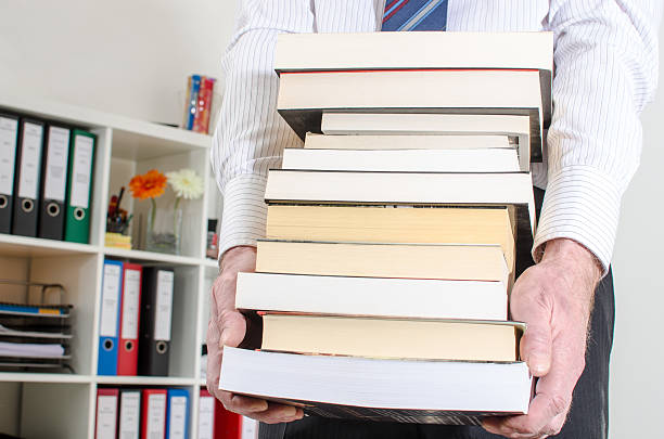 istock Man carrying a pile of books 473920134