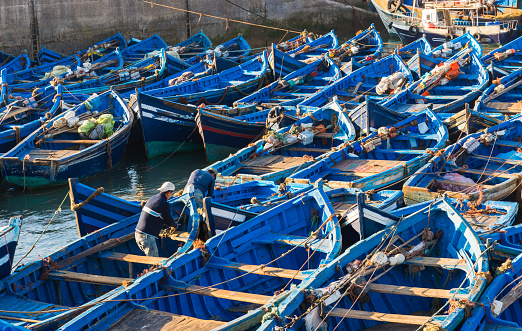 Essaouira, Morocco - March 14, 2014: Two men prepare the blue boats for fishing which park at of Skala du Port on March 14, 2014 in Essaouira, Morocco