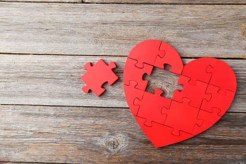 Red puzzle heart on grey wooden background