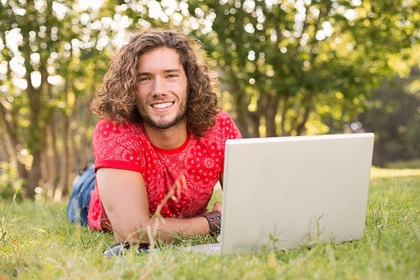 istock Handsome hipster using laptop in the park 473935908